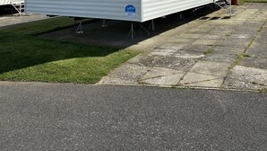 Ett hus på hjul med ett platt tak, stora fönster och en liten veranda.