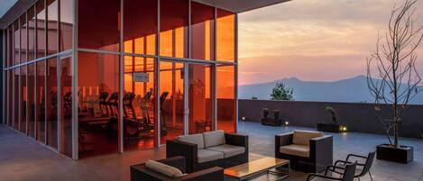 Un área de estar al aire libre moderna, con cerramiento de vidrio, una mesa de comedor y sillas.