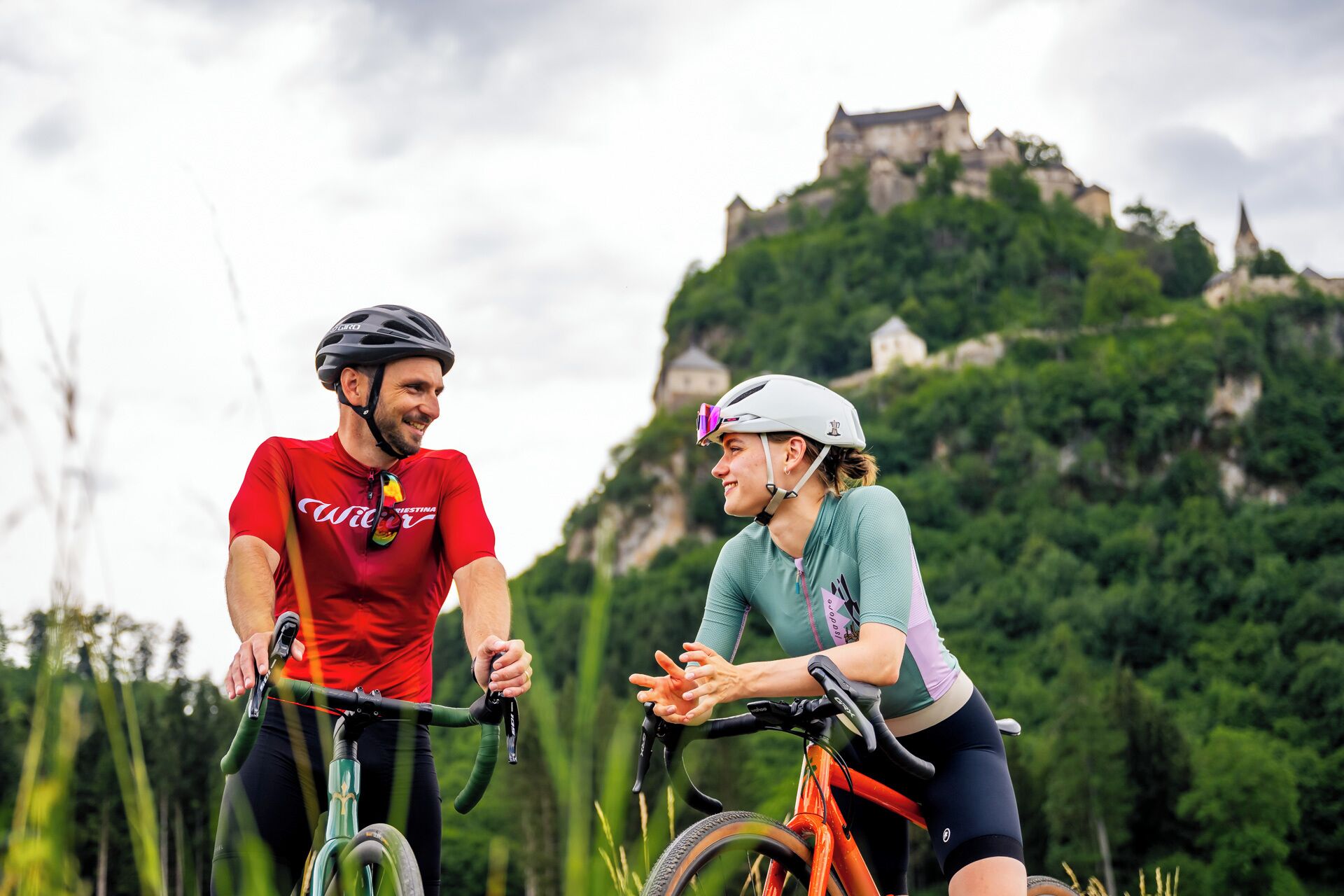 Two cyclists on a trail with a castle in the background.