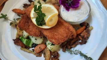 A plate of food with breaded cutlets, vegetables, and a side of sauce.