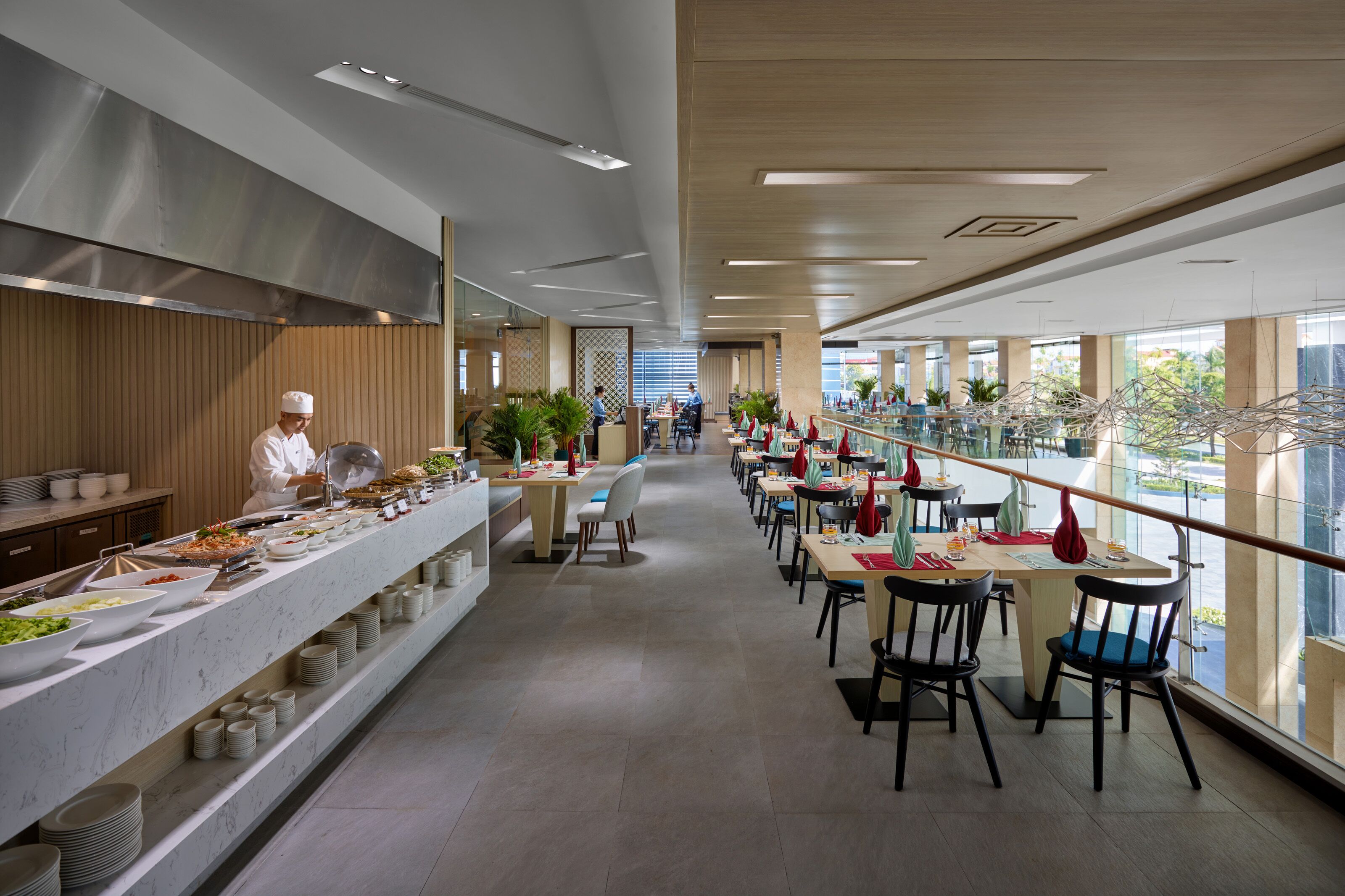 A modern dining area with a long counter, multiple tables, and chairs.