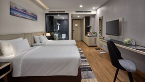 Camera d'albergo con due letti, una scrivania con una sedia, una TV e un bagno visibile attraverso una porta aperta.