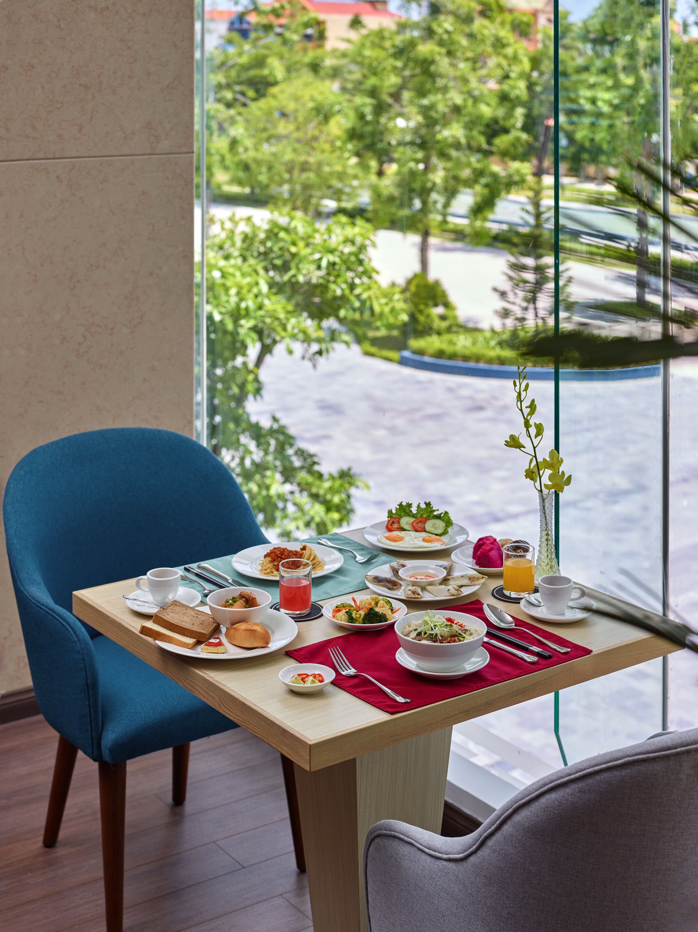 A dining table with various dishes and a view of a green landscape through a window.