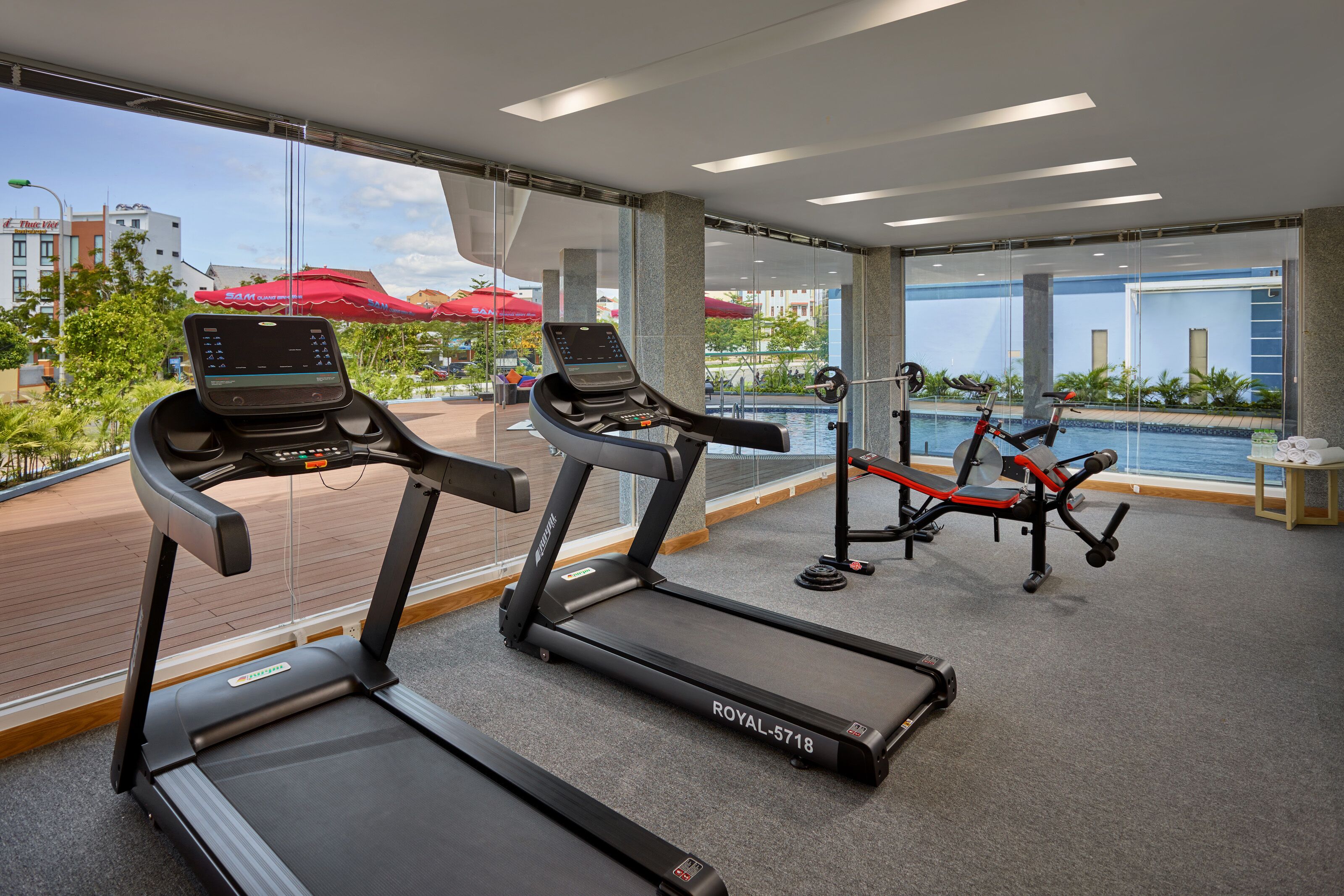 A gym with treadmills, a weight bench, and a rowing machine.