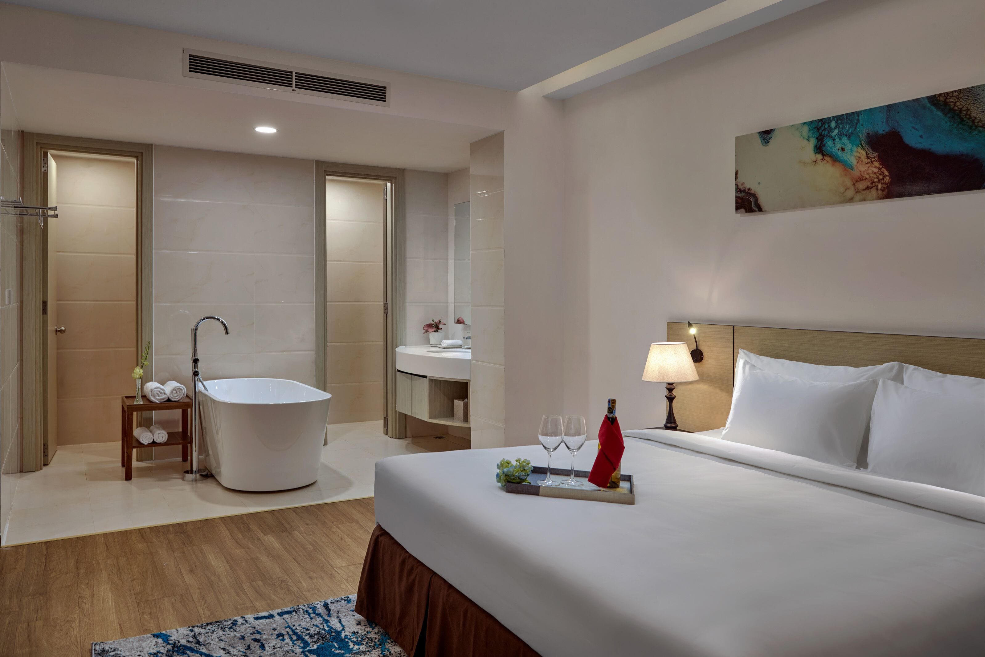 Habitación de hotel con una cama grande, una bañera, un tocador y un cuadro en la pared.