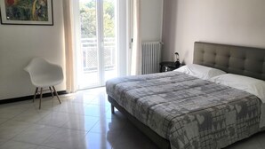 Un dormitorio con cama, una silla, un radiador y una puerta que da a un balcón.
