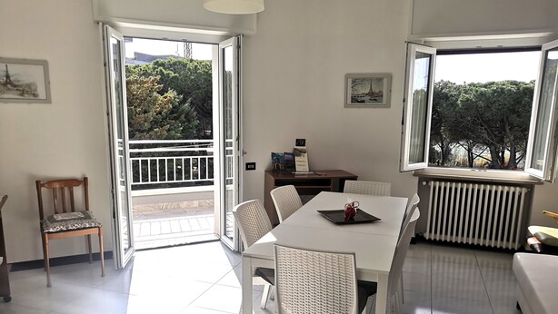 Una habitación luminosa con una mesa de comedor, sillas, un radiador y una butaca con cojín.