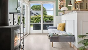 Ein gemütliches Zimmer mit Kamin, einer Bank und Blick ins Freie.