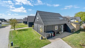 Ein modernes Wohngebäude mit Satteldach, einer kleinen Veranda und einer Garage.