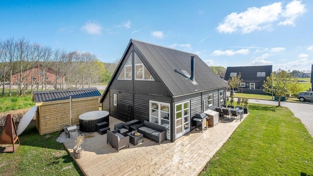 Ein modernes Haus mit einer großen Terrasse, Sitzgelegenheiten im Freien und einem Whirlpool.