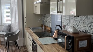 Une cuisine moderne équipée d’un four encastré, d’une bouilloire et d’un grille-pain.