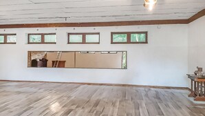 Ein geräumiger Raum mit Holzboden, einem großen Spiegel und mehreren kleinen Fenstern.