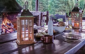 Enjoy a warm meal under the stars with a rustic dining setup featuring a beautifully set table and a crackling fire.
