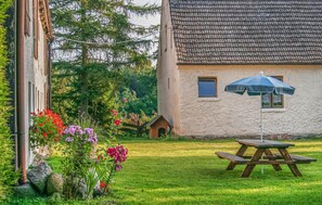 Relax in a serene outdoor setting with a traditional house, picnic table, and beautifully manicured lawn.