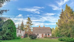 Ein traditionelles Haus mit Ziegeldach, umgeben von einem gepflegten Rasen und hohen Bäumen.