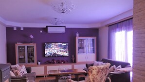 Una sala de estar con un sofá, un sillón y un televisor en la pared.