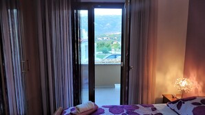 Un dormitorio con cama, mesita de noche y vistas al exterior por una puerta corrediza.