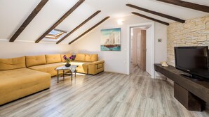 A cozy living room with a sofa, a small table with a vase, a painting, and a TV on a wooden stand. - Nice home in Zubovici (Zubovici)