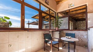 A balcony with a wooden pergola, a potted plant, two chairs, a small table, and a stone wall. - Nice home in Zubovici (Zubovici)
