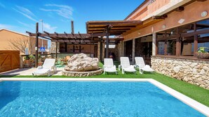 A swimming pool with lounge chairs, a pergola, and a stone wall. - Nice home in Zubovici (Zubovici)