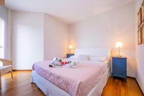 Un dormitorio ordenado con cama, mesitas de noche y un banco.