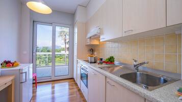 A modern kitchen with a large window, a built-in oven, and a stainless steel sink.
