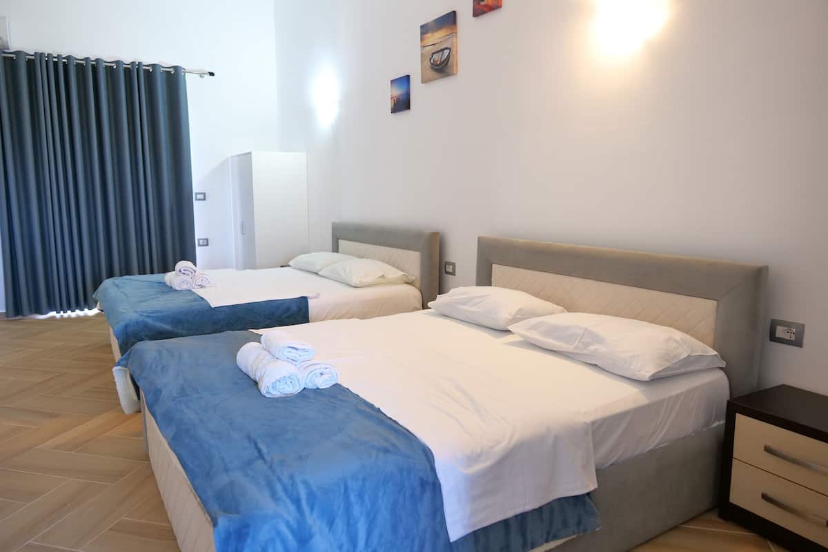 Une chambre d’hôtel avec deux lits, une table de chevet et une armoire.