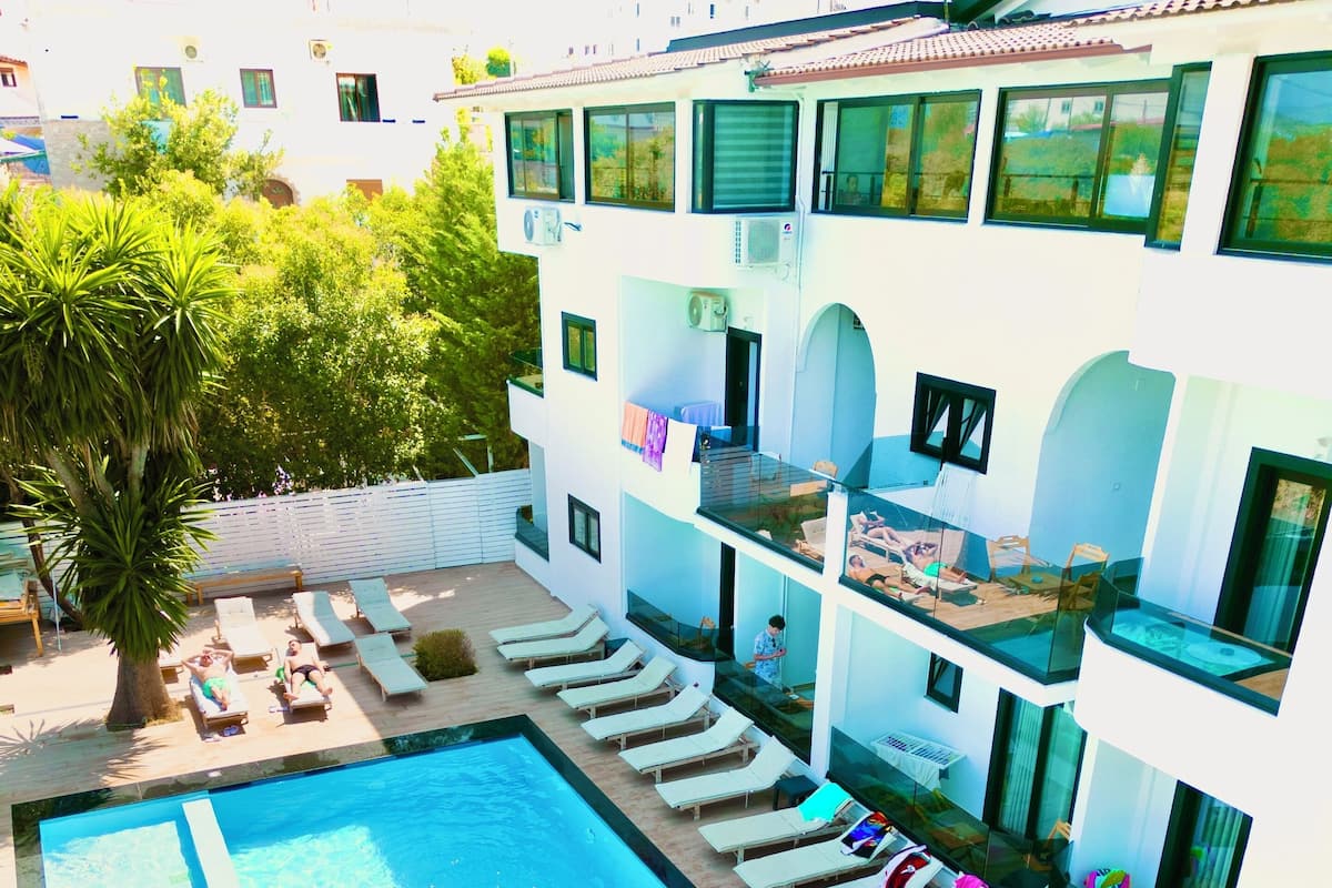 Un hôtel moderne doté d’une piscine, de chaises longues et d’un bâtiment à deux étages avec des balcons.