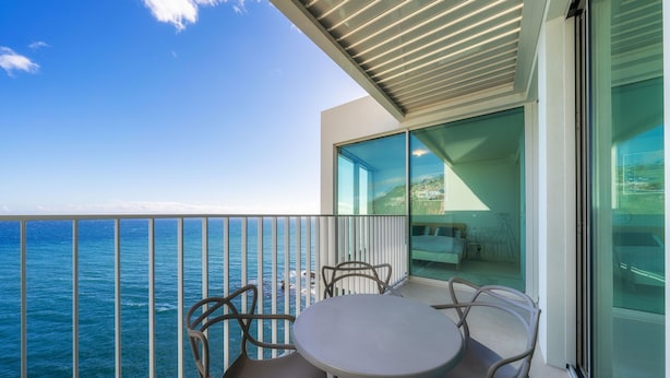 Un balcone con tavolo e sedie vista mare.