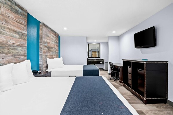 Ett hotellrum med två sängar, ett skrivbord, en stol, en TV och en garderob.