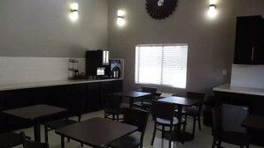 A dining area with tables and chairs, a coffee machine, and a window with blinds. - Surestay Hotel by Best Western Buena Park Anaheim (Buena Park)