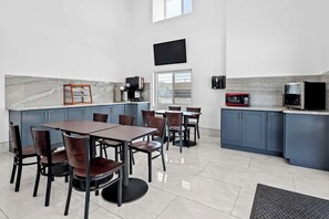 Una cocina moderna con encimera de mármol, armarios oscuros y un comedor con sillas y mesa.