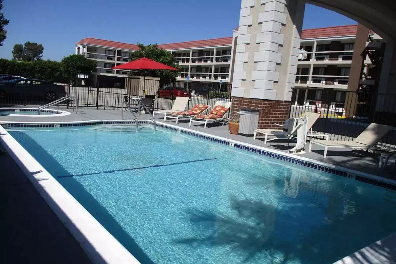 A swimming pool with lounge chairs and a red umbrella.