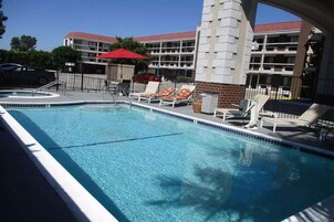 A swimming pool with lounge chairs and a red umbrella.