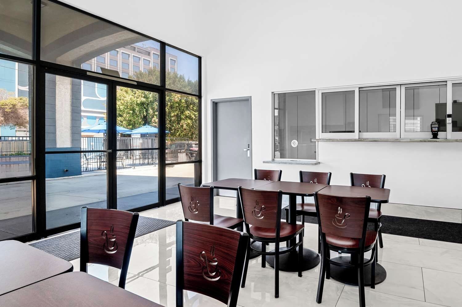 Un comedor moderno con amplios ventanales, interior blanco y vistas al exterior.
