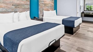 Una habitación de hotel moderna con dos camas, un baño y una kitchenette.