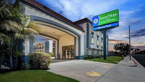 A SureStay hotel entrance with a large sign, a covered walkway, and a well-maintained lawn. - Surestay Hotel by Best Western Buena Park Anaheim (Buena Park)