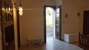 A hallway with a bench, a door leading outside, and a small white cabinet. - Il Trullo del Lauro (Laureto di Fasano)
