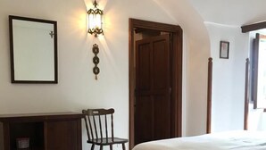 A bedroom with a bed, a wooden desk, a chair, and a wardrobe. There is a wall-mounted light fixture above the desk. - Il Trullo del Lauro (Laureto di Fasano)