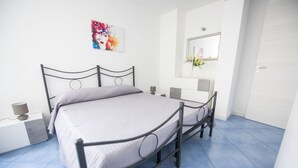 Une chambre à coucher comprenant un lit, une table de chevet, une lampe et un miroir fixé au mur.