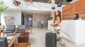 Un moderno vestíbulo de hotel con una recepción, zona de estar y una escalera.