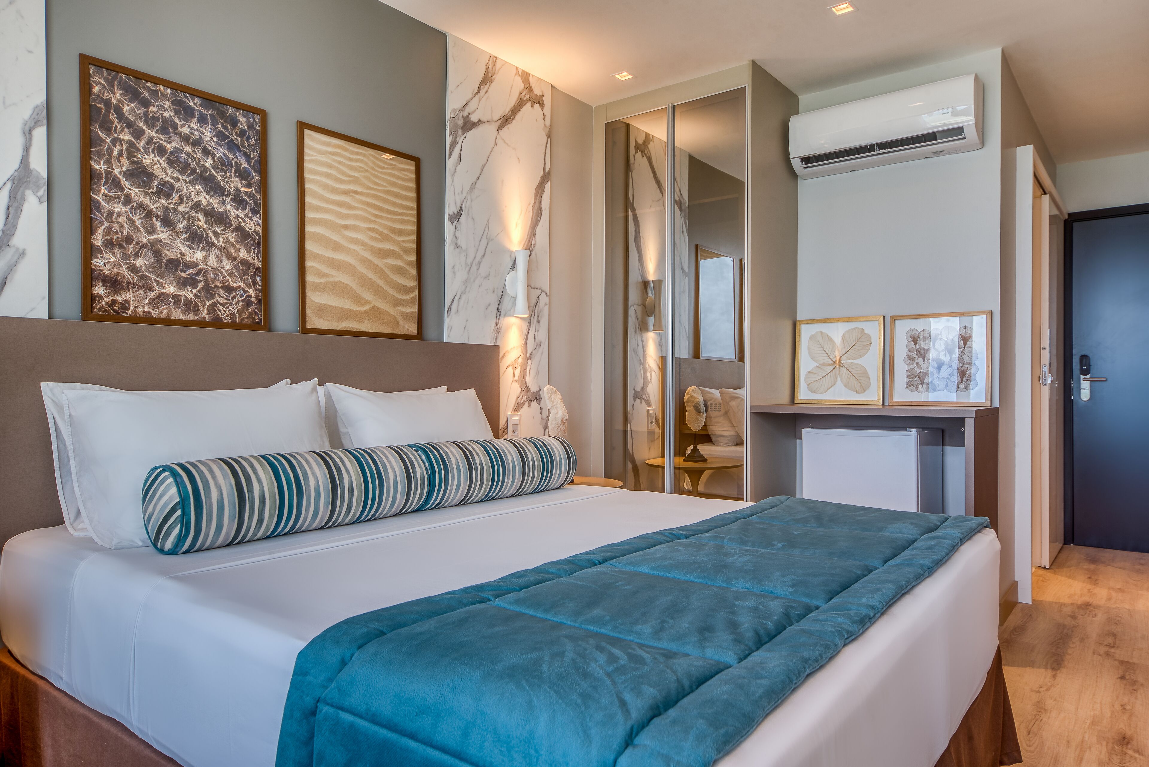 Una habitación de hotel moderna con una cama grande, una mesita de noche, un espejo y un pequeño escritorio con una silla.