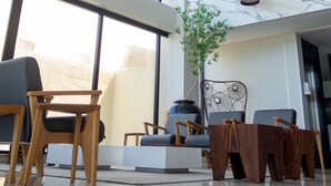 A modern lobby with wooden furniture, large windows, and a marble wall. - Hotel Água de Coco (Maceió)