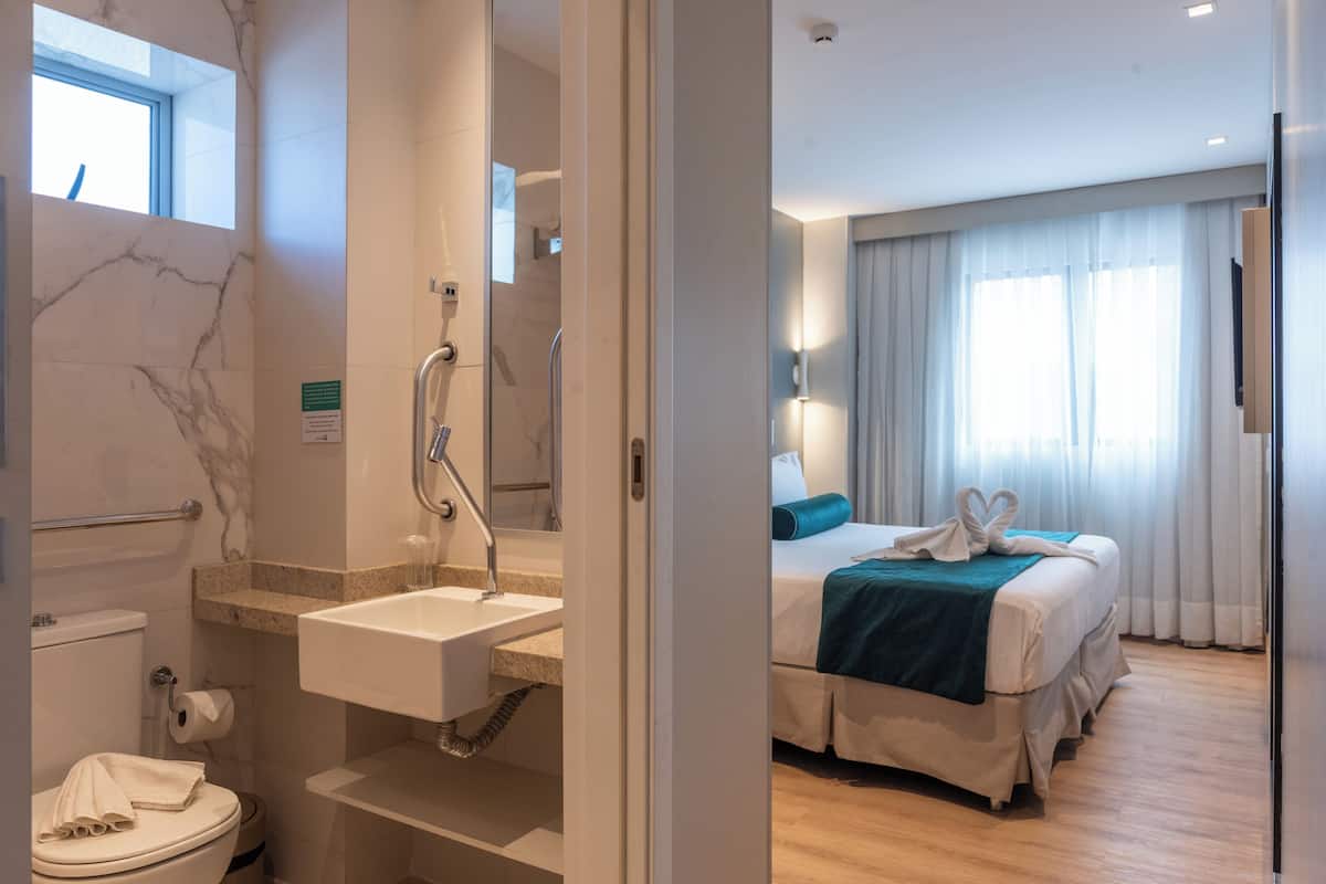 A hotel bathroom with a marble wall, a sink, and a toilet.