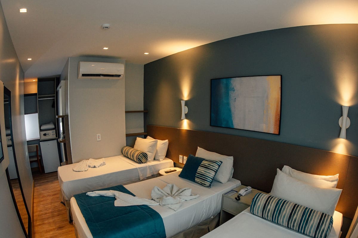 A hotel room with two beds, a desk, and a kitchenette.