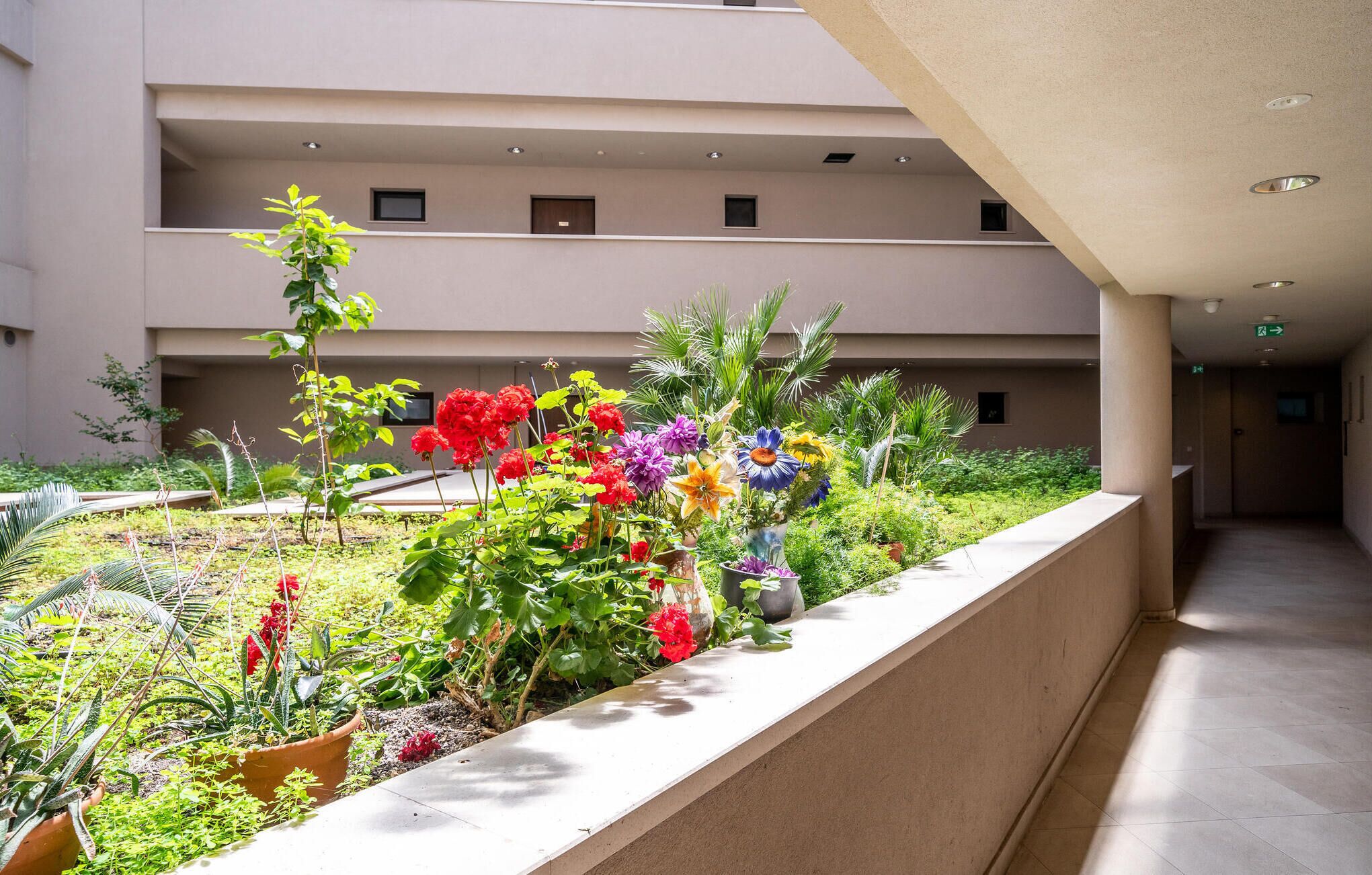 Ein mehrgeschossiges Gebäude mit einem Balkongarten, der verschiedene Pflanzen und Blumen zeigt.