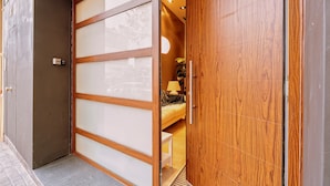 Una habitación de hotel moderna con una puerta corredera, una cama, una mesita de noche y una lámpara.