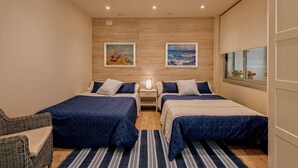 Habitación de hotel con dos camas, una mesita de noche, una lámpara y dos cuadros en la pared.
