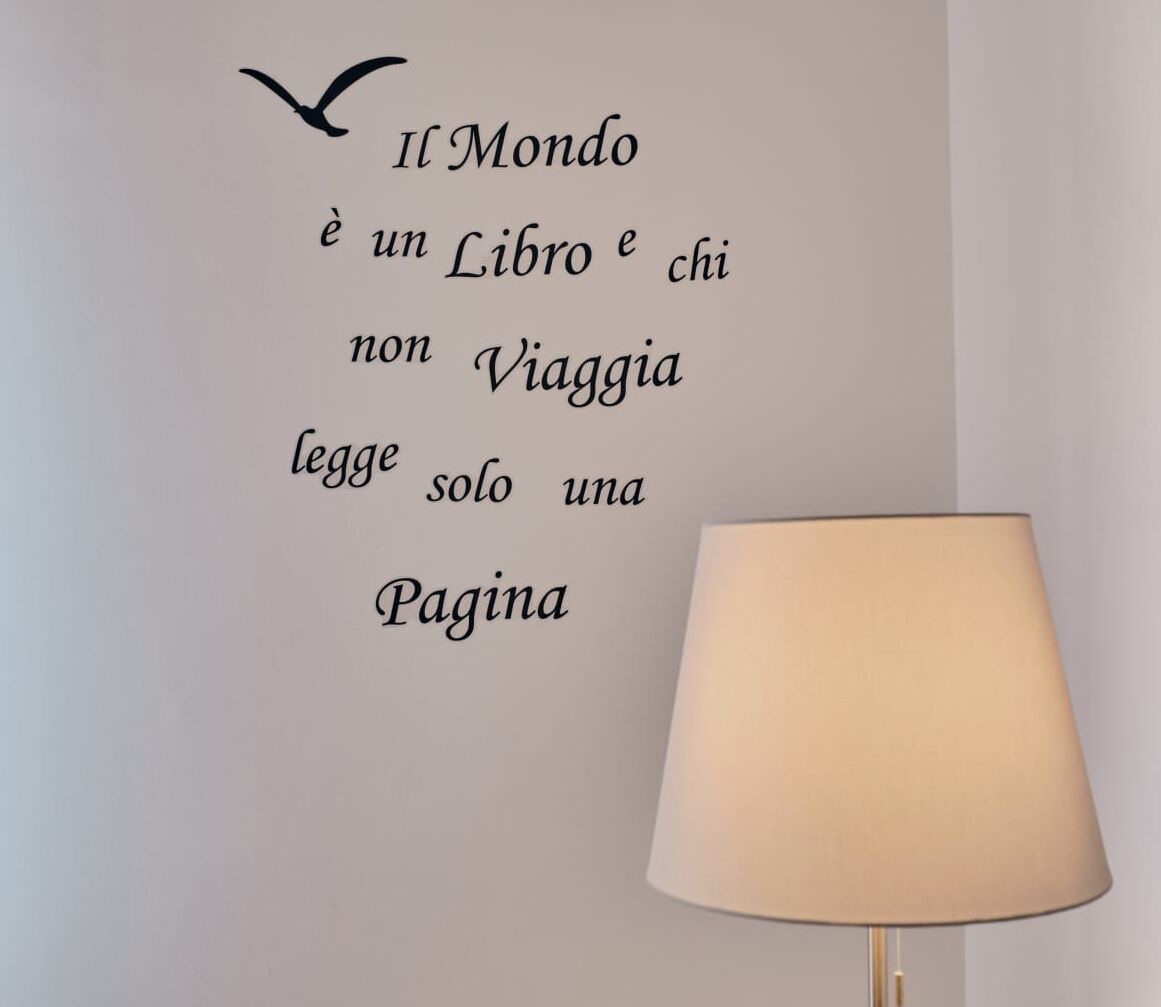 A wall with a quote in Italian, a lamp, and a bird illustration.
