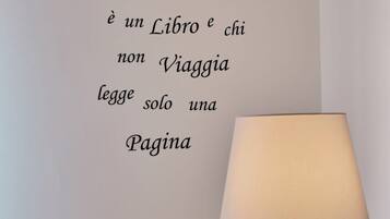 A wall with a quote in Italian, a lamp, and a bird illustration.